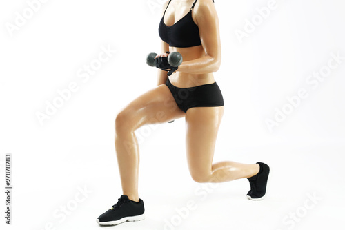 Umięśnione kobiece ciało, trening z hantlami. Kobieta w stroju sportowym podnosi ciężarki.