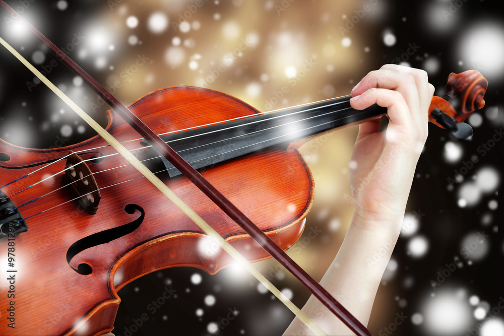 Naklejka premium Beautiful young girl with classical violin on bright background over snow effect