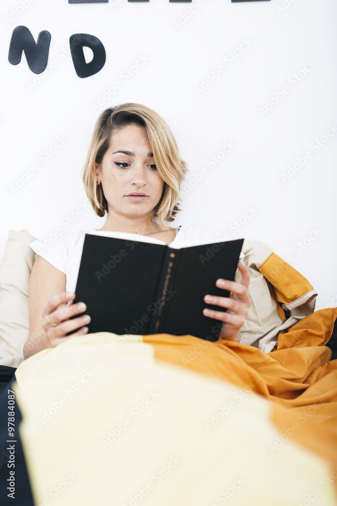 Young student reading book in bed Young student reading book in bed