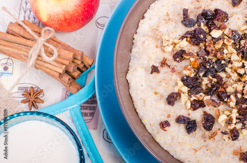 Breakfast set. A bowl of barley porridge with cocnut oil, vegetarian milk, walnuts, raisins, cinnamon on sackcloth, canvas, spoon, apple, glass of vegetarian milk. photo