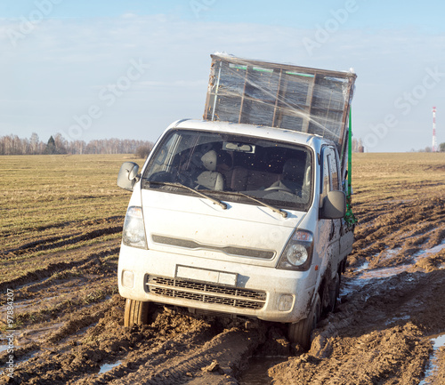 Off-road truck with furniture settles down in mud on dirty road in fallow field © shujaa_777
