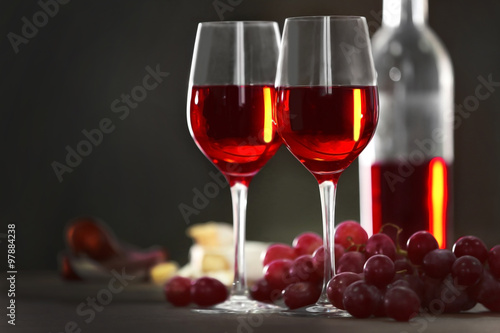 Two wineglasses with grape on the table over dark background, close-up