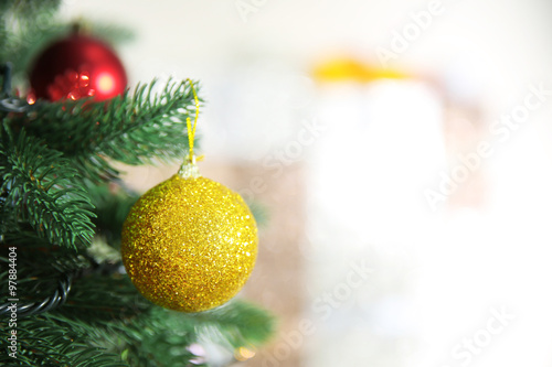 Christmas golden bauble on a fir tree over blurred background, close-up