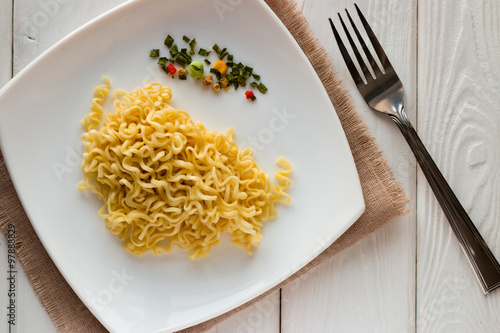 white plate with instant noodles and fork on a white background