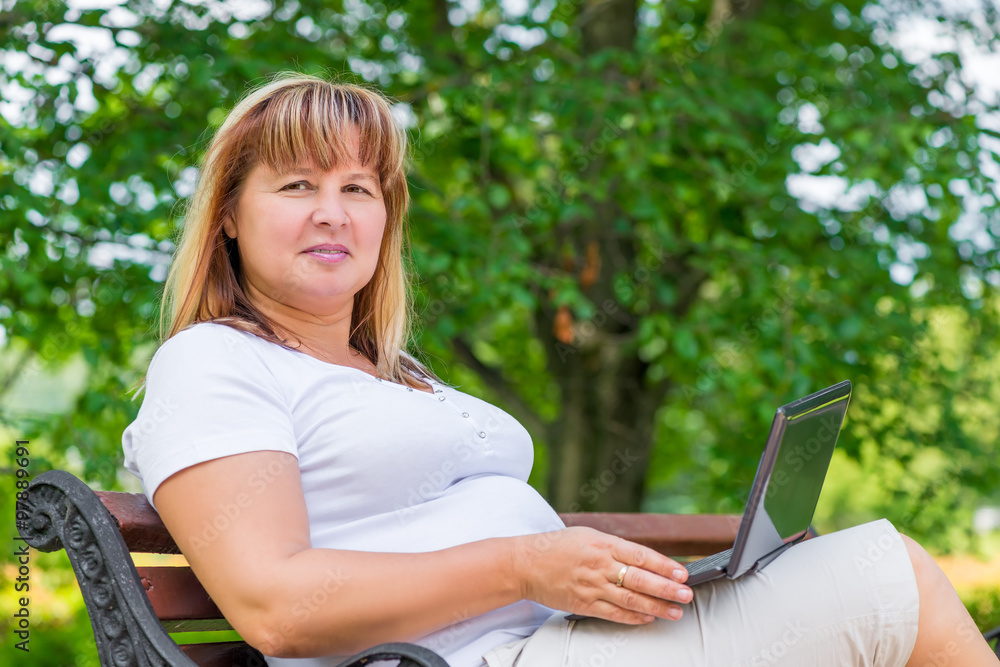 portrait of a woman on a bench in the park with a laptop portrait of a woman on a bench in the park with a laptop