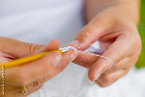female hands close-up with crochet hooks and cotton thread
