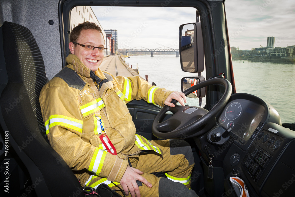 Fototapeta premium Portrait of happy firefighter driving firetruck in Germany