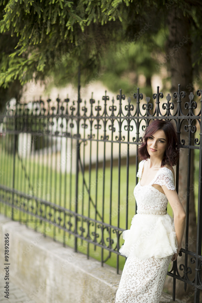 Young woman in white drress by the fence