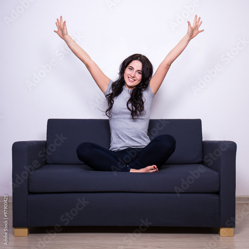 happiness concept - happy woman sitting on sofa