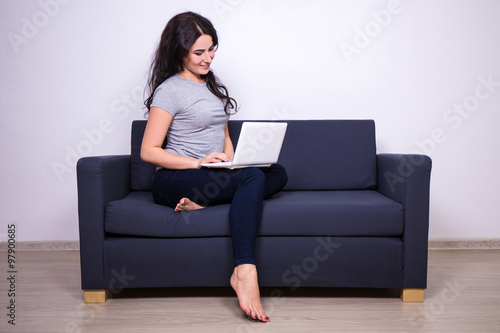 portrait of pretty woman sitting on sofa and using computer at h