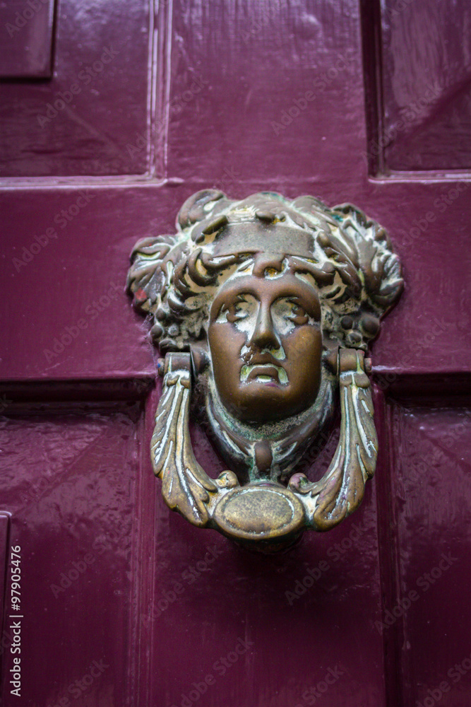 Beautiful head door knocker on the old wooden door