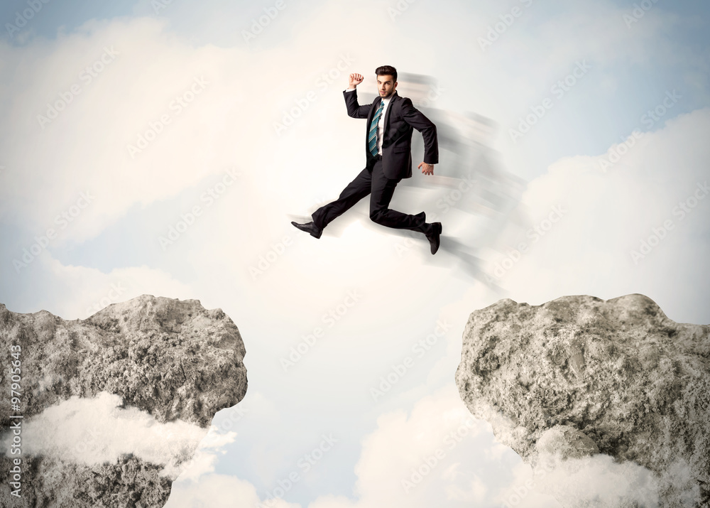 Happy business man jumping over a cliff Happy business man jumping over a cliff