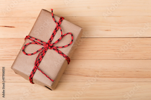 Present Wrapped With Brown Paper and String on Wood Background