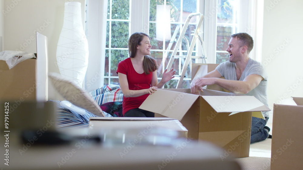 Happy young couple unpacking boxes, moving into new home Happy young couple unpacking boxes, moving into new home