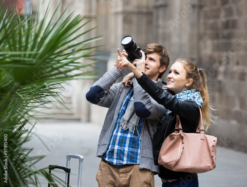 Vászonkép Two travellers with digital camera walking through city street