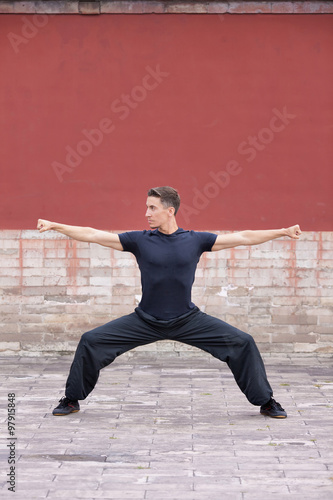 Martial arts master practising against red ancient Chinese wall, Beijing, China