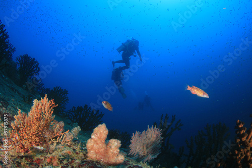Scuba divers diving on coral reef with fish sea ocean underwater