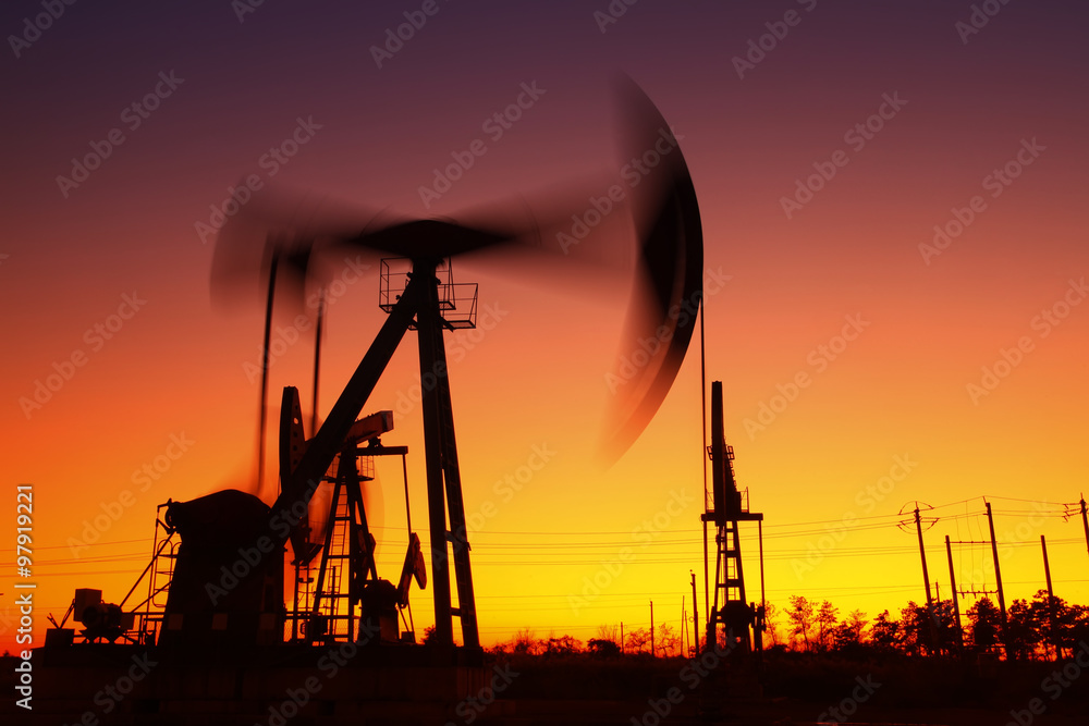 Oil field scene, the evening of beam pumping unit in silhouette