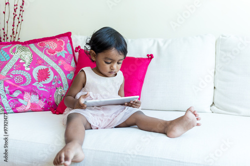 Indian girl watch on tabet and sitting on sofa photo