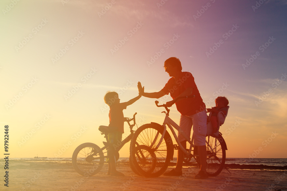 Obraz premium Biker family silhouette, father with two kids on bikes