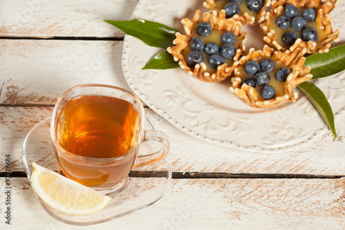 Cup of tea with waffle baskets stuffed with lemon cream with blueberries.