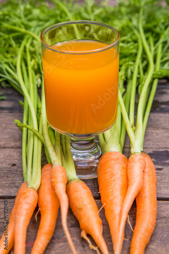 Fresh-squeezed carrot juice on wooden background