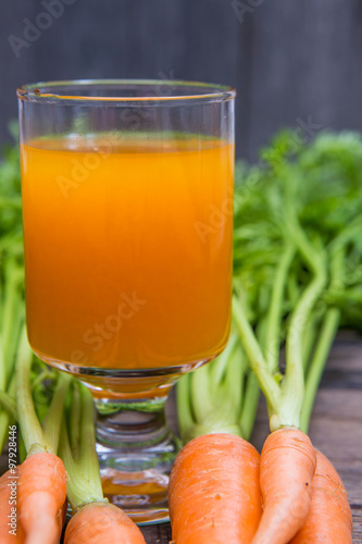 Fresh-squeezed carrot juice on wooden background