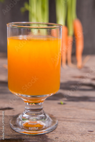 Fresh-squeezed carrot juice on wooden background