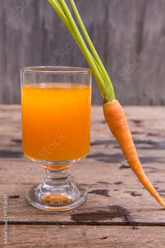 Fresh-squeezed carrot juice on wooden background