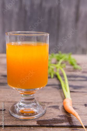 Fresh-squeezed carrot juice on wooden background