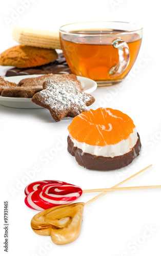 Isolated image of cup of tea, candy and cookies on a white background closeup