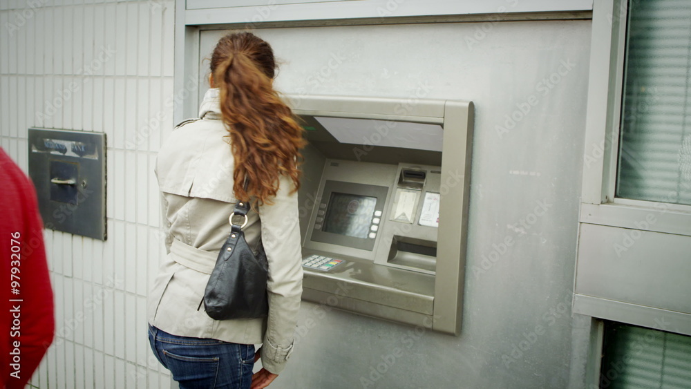 suspicious woman taking cash from an ATM machine suspicious woman taking cash from an ATM machine