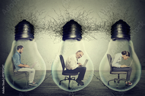 Company employees sitting in row inside electric lamp light bulb using laptop photo