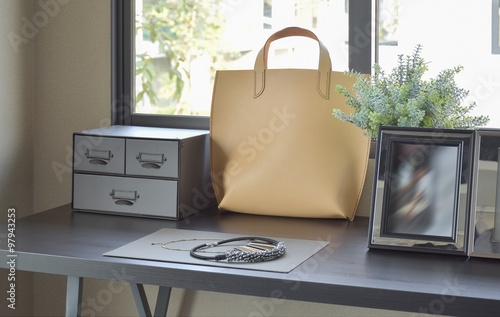 female's accessories with handbag and jewelry on wooden dressing photo