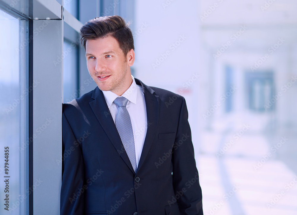 Portrait of businessman standing near window in office Portrait of businessman standing near window in office