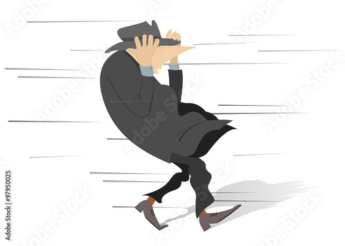 Windy day. Man tries to keep a hat on his head
