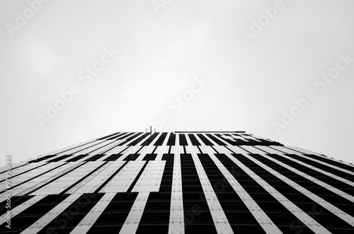 perspective in underside angle view of silhouette glass building against sky background