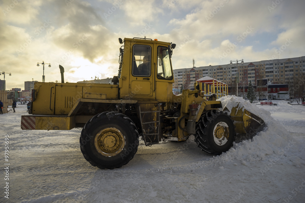 Tractor shovel snow in  pile on the street.