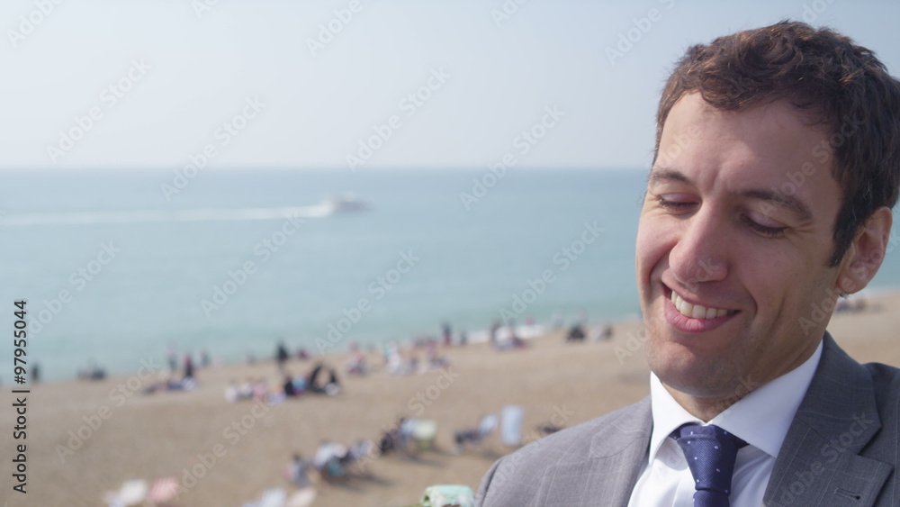 Portrait of smiling businessman talking on mobile phone at the beach. Shot on RED Epic. Portrait of smiling businessman talking on mobile phone at the beach. Shot on RED Epic.
