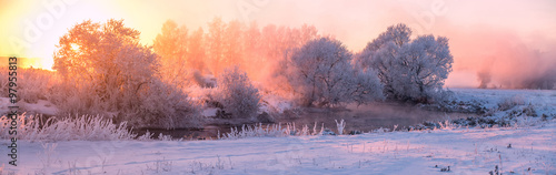 Fairy winter landscape on river . The sun shines through frozen trees . beautiful winter sunrise on lake . stitched panorama . Magic winter sunlight .