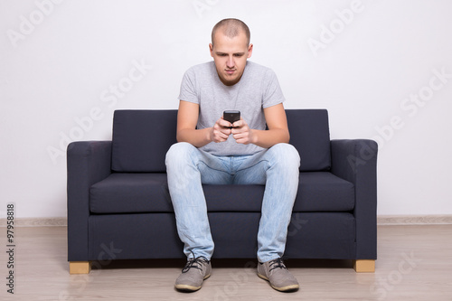 handsome man sitting on sofa with mobile phone