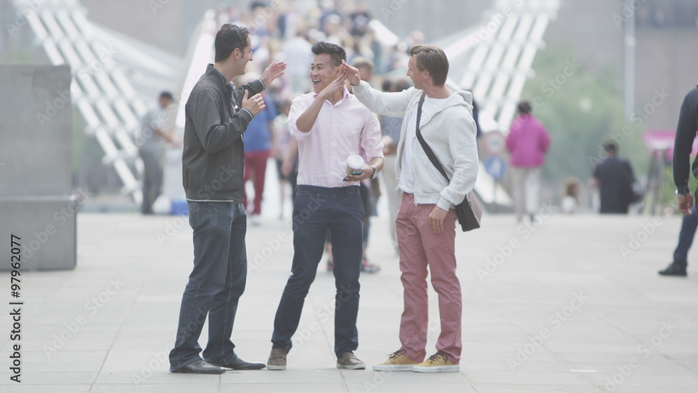 Young man with his friends in the city receives a text message giving good news Young man with his friends in the city receives a text message giving good news