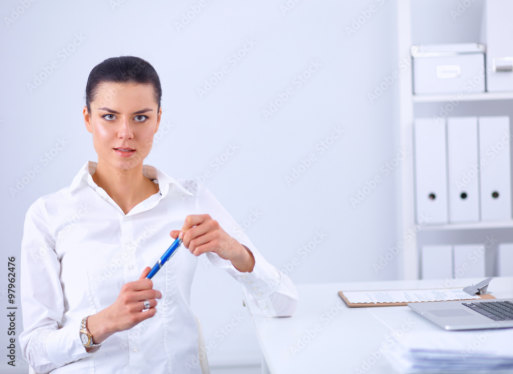 Attractive businesswoman sitting on a desk with laptop in the office Attractive businesswoman sitting on a desk with laptop in the office