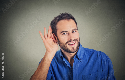handsome nosy business man secretly listening in on conversation, hand to ear