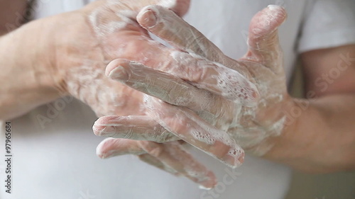 A man works soapy lather into his hands.