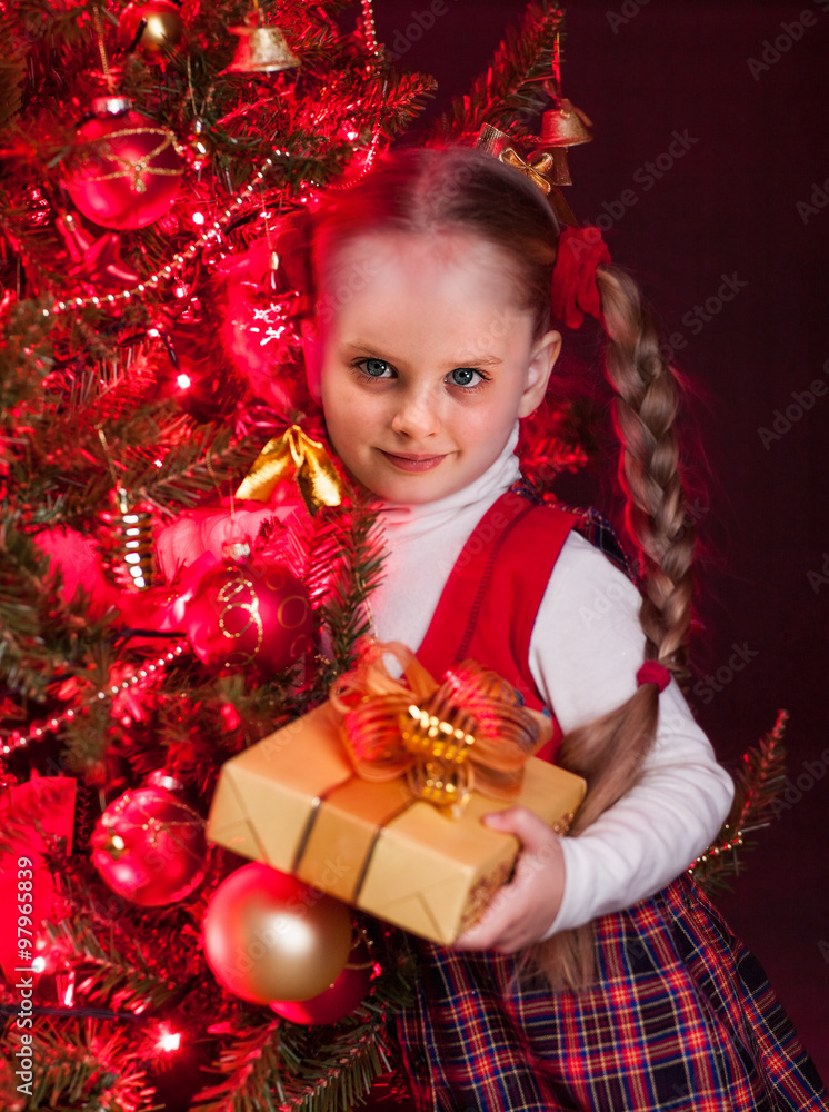 Child with gift box near Christmas tree. Child with gift box near Christmas tree.
