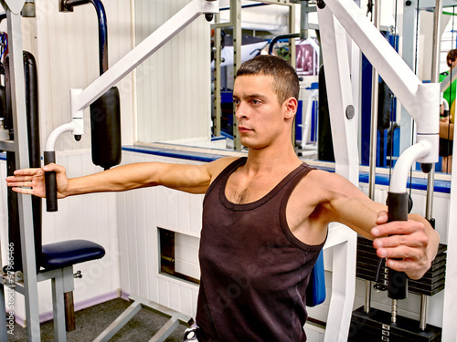 Man working his arms on training apparatus at gym. 