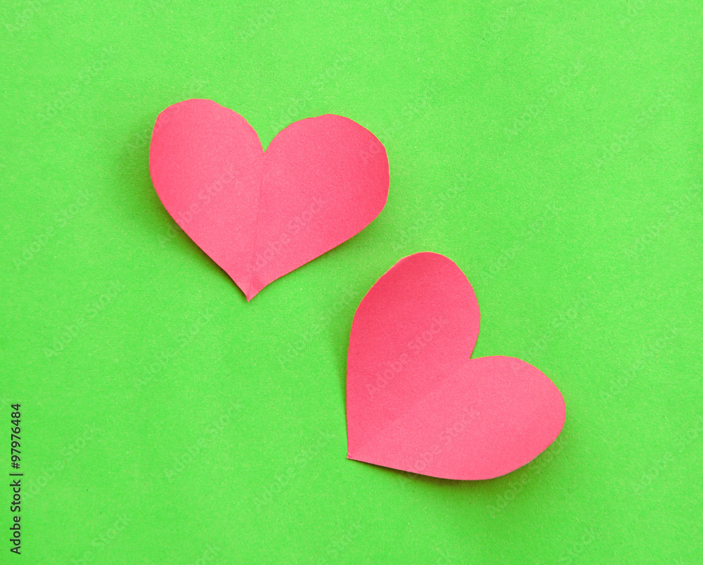 Pink paper hearts on green background