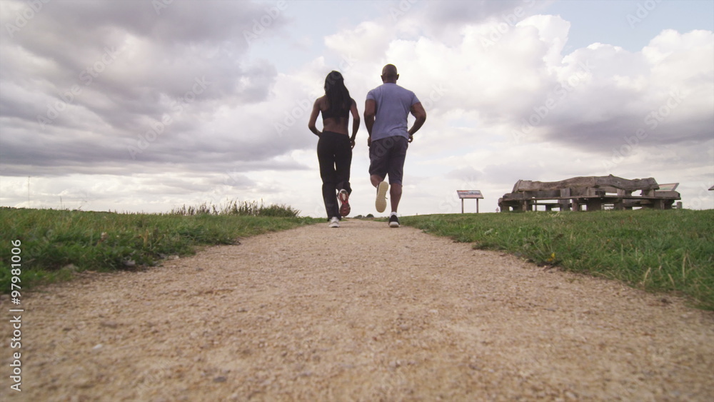 Young sports man and woman running into the distance in slow motion Young sports man and woman running into the distance in slow motion