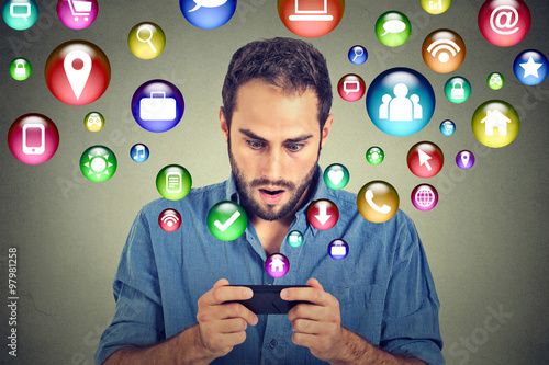 Shocked man using texting on smartphone application icons flying out of cellphone